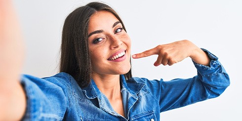 Smiling woman pointing to her white teeth