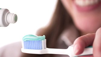 Lady applies toothpaste to a toothbrush