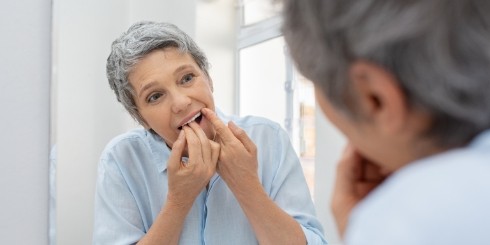 Woman flossing teeth before professional dental cleaning