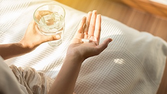 Woman holding a pill and water