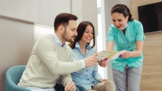 Dental team members and patients discussing the cost of veneers compared to other treatments